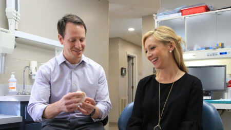 Dr. David Wickness uses a model of teeth to explain dental treatment to a patient.